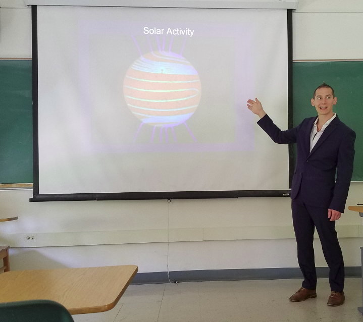Marshall giving a presentation, standing in front of a projected image titled Solar Activity.